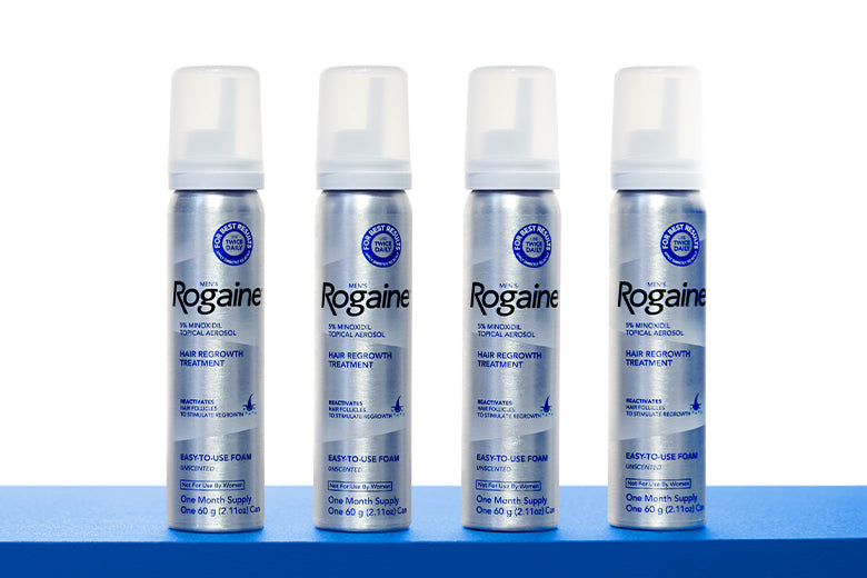 Four bottles of ROGAINE® Men's Topical Foam on a blue shelf with a white background