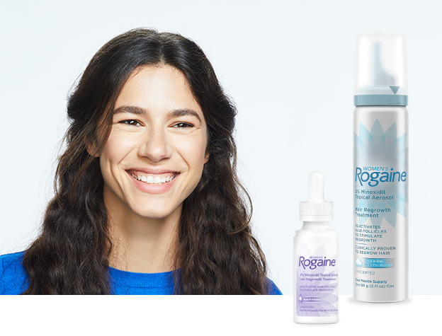 Woman with long brown wavy hair smiling wearing a blue shirt. Featuring bottles of Women's Rogaine Foam and Topical Solution.